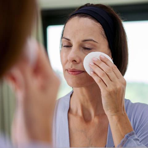 Woman cleanses face with pad