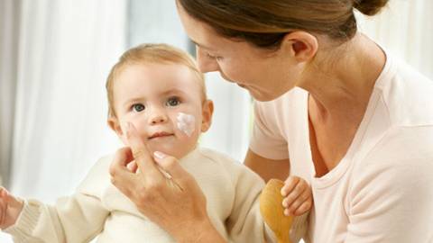 Mommy applies face cream on baby