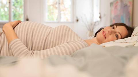 Pregnant woman lies in bed