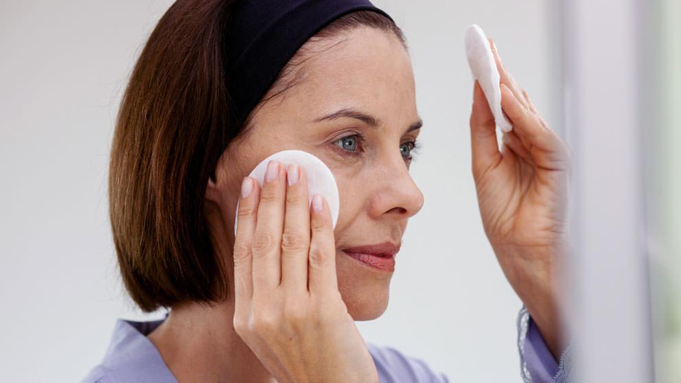 Woman cleanses face with pads