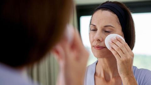 Woman cleanses face with pad